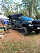 On The Horizon 1.9 Penthouse rooftop tent open on a Chevrolet at a camp site with chairs out