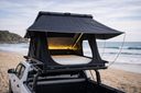 On The Horizon 1.4 hard shell rooftop tent open on a ute at the beach, interior light on