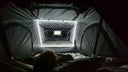 A child in bed watching a tablet in the clear window of the end pocket inside the 1.5 Pro, LED strip lit